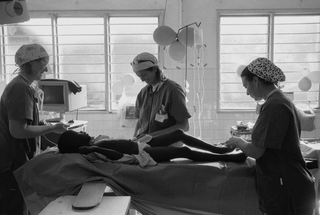 Uganda, 103-018-16 Tre medici assistono un bambino sdraiato a letto, 2008 Ospedale St. Francis, Nkokonjeru (Uganda)