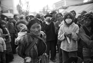 Tibet, 102-032-05 Una donna con un bambino in spalla, circondati da altre persone del luogo, 2004 Shigatse (Tibet)