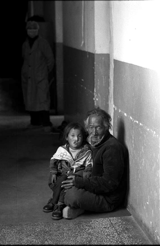 Tibet, 102-022-12
Un uomo e il nipote seduti per terra in un ospedale e un medico dietro di loro, 2004
Shigatse (Tibet)