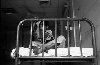 Bangladesh, 103-030-14
Bambina seduta su un letto in interno, 2009
Dacca (Bangladesh)