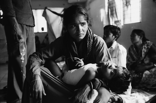 Bangladesh, 103-026-18
Bambina con flebo in braccio a una donna in interno, 2009
Dacca (Bangladesh)